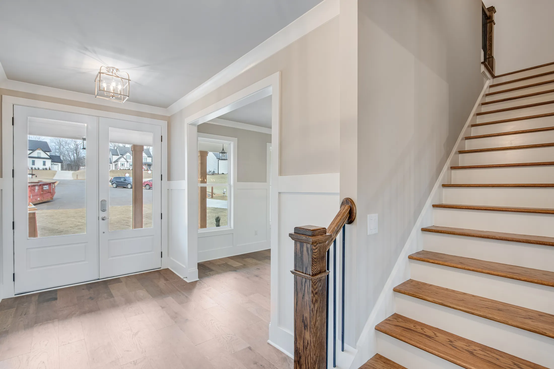 Foyer with double doors and a staircase with a wood railing