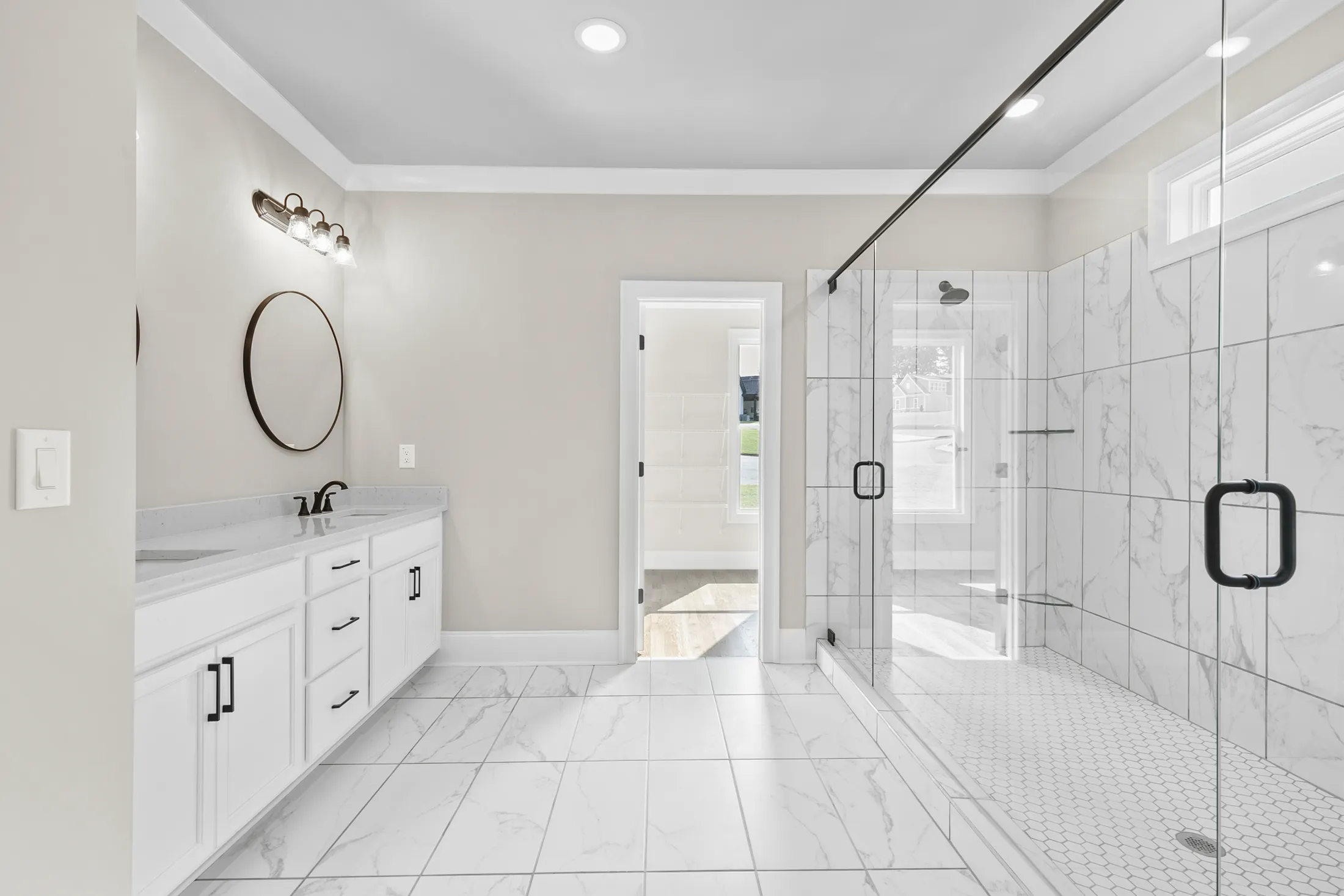 Bathroom with a double vanity, round mirrors and a tiled glass shower