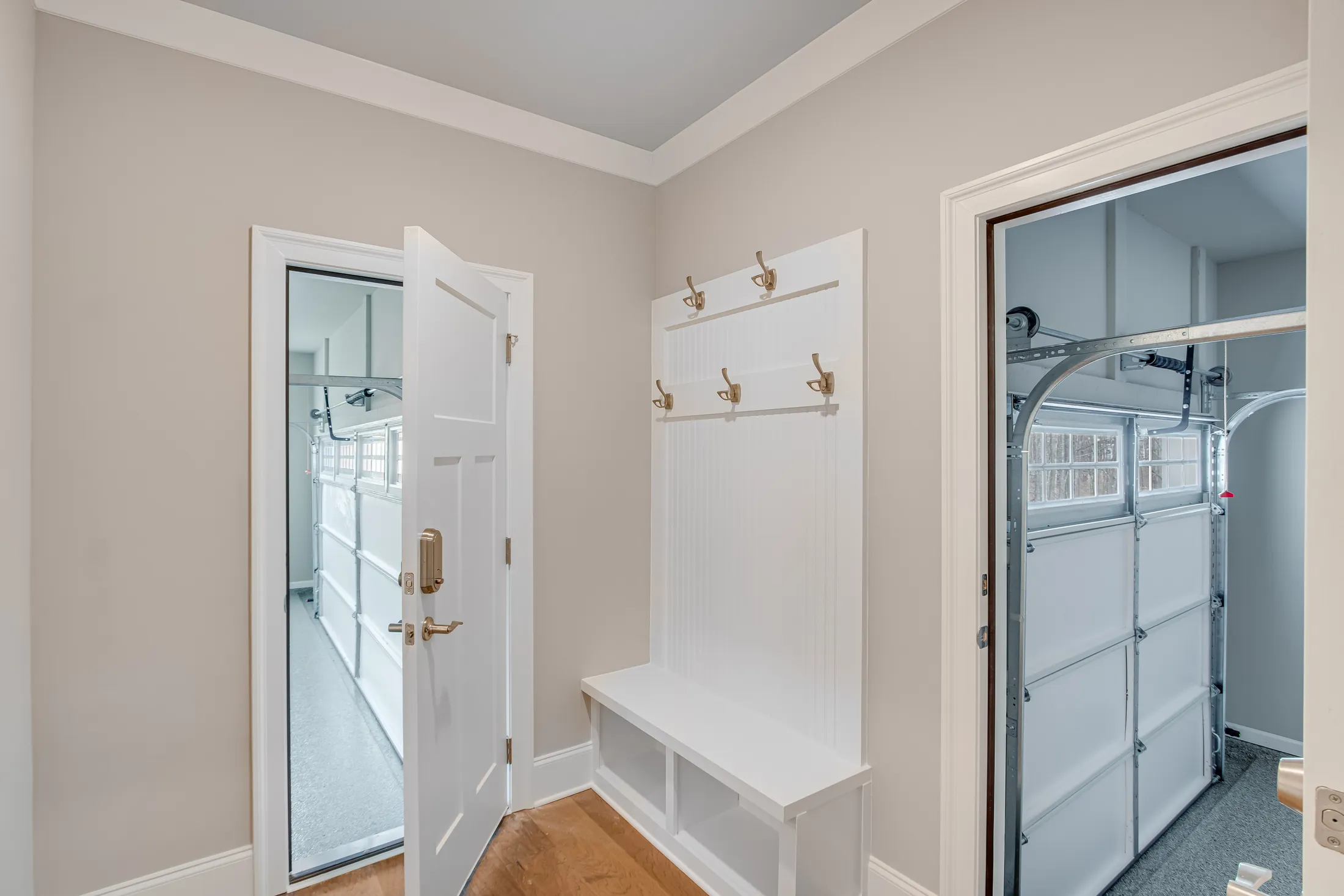 Mudroom with coat hooks and a built-in bench beside the garage door