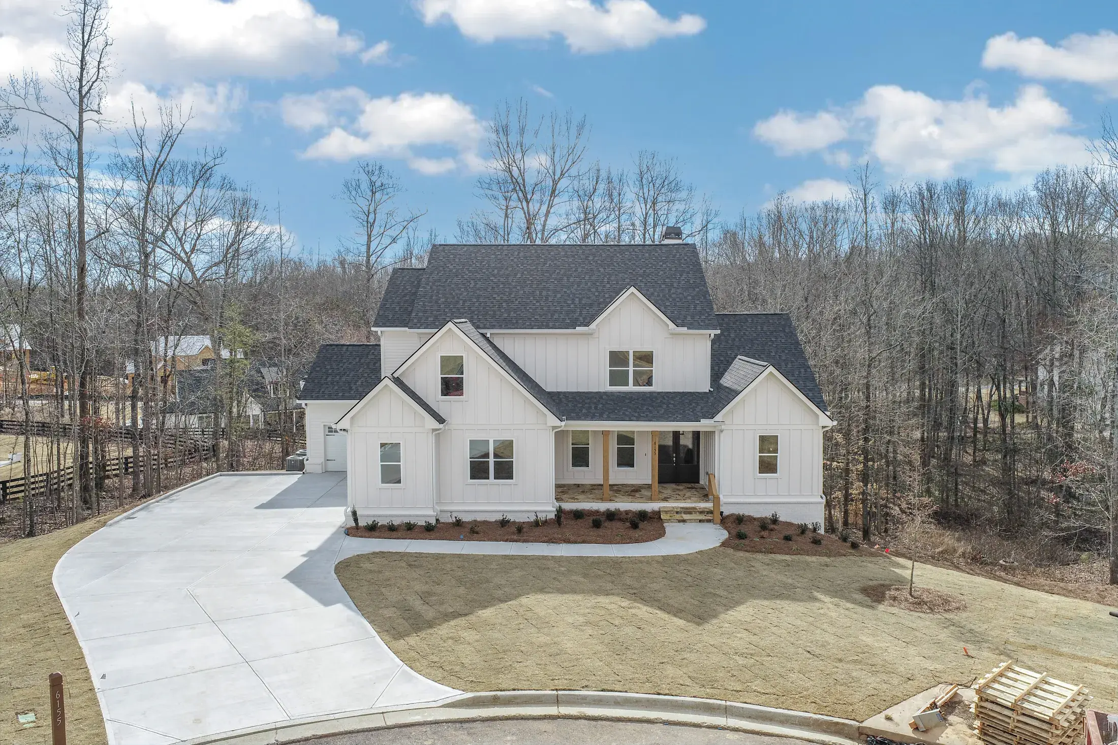Aerial view of a custom home with a concrete driveway in the woods