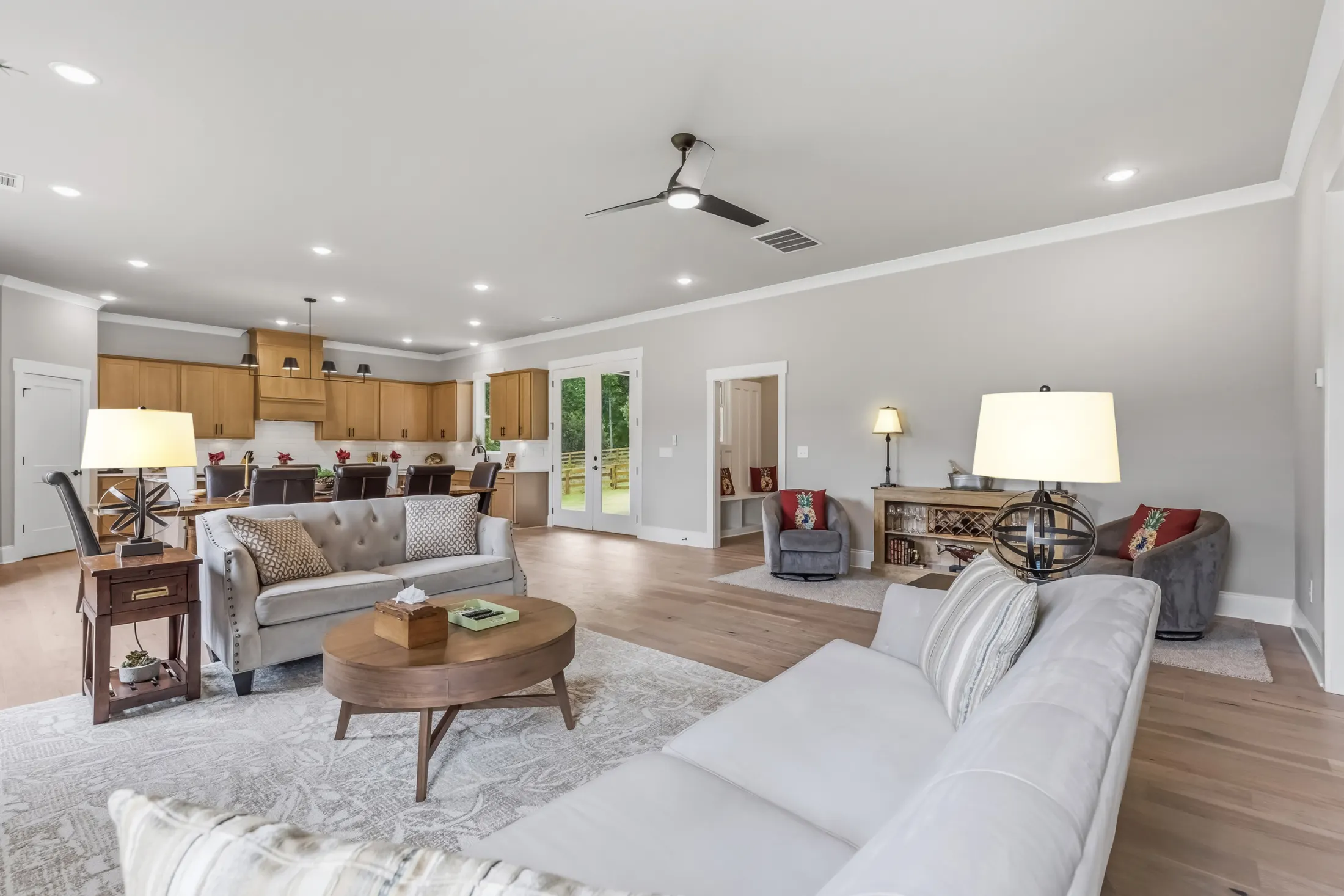 Open living room with tufted sofas, a round coffee table and the kitchen beyond