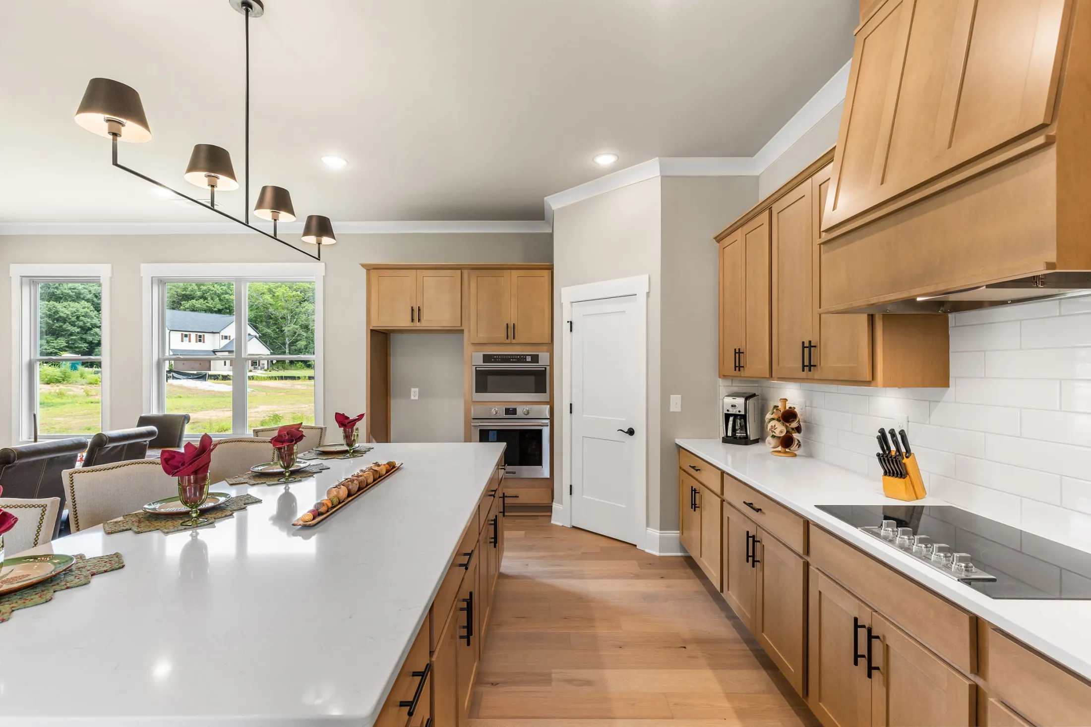 Kitchen with wood shaker cabinets, a large white quartz island, wall ovens and a white subway tile backsplash